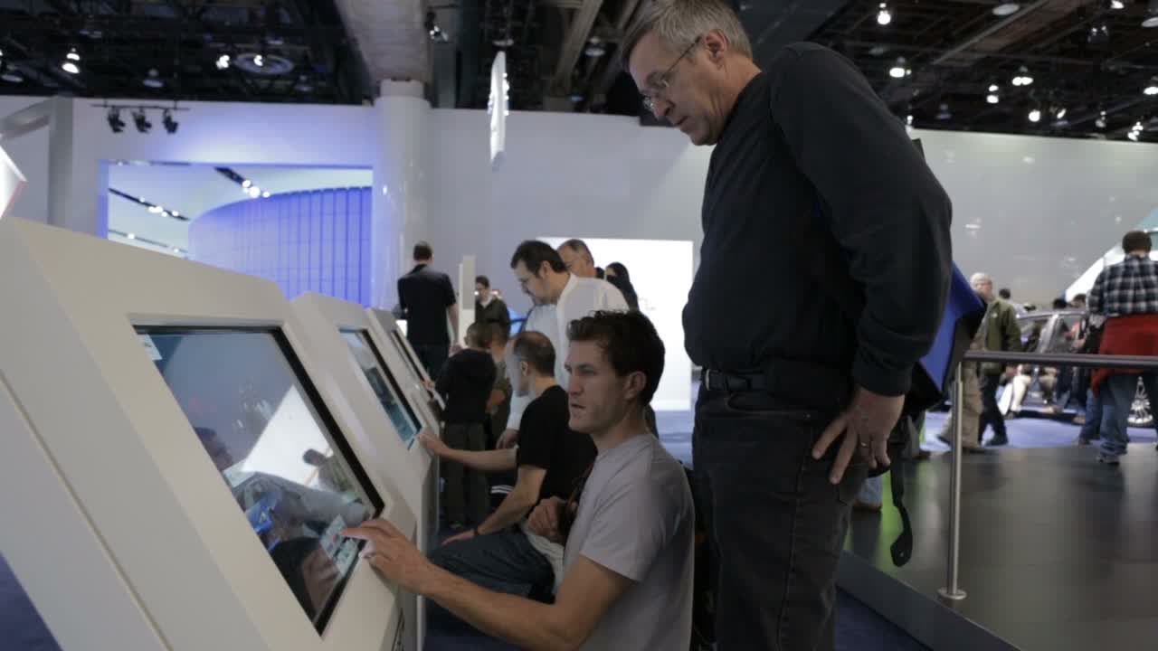Visitors at a bank of touchscreen kiosks on a show floor